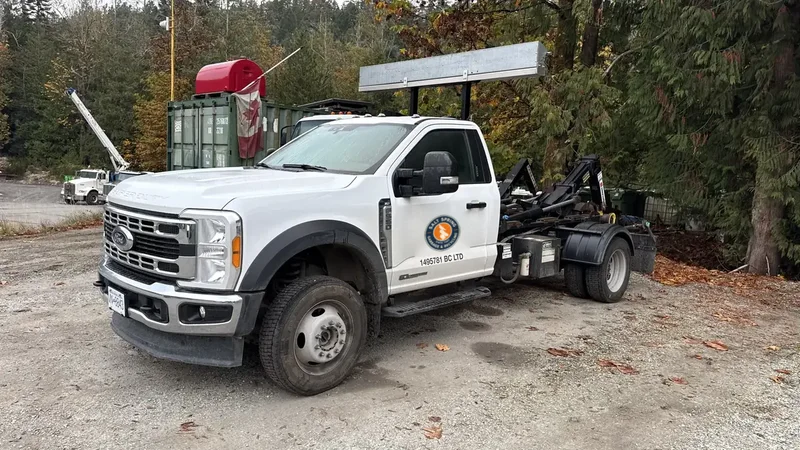 White Ford F-550 hook-lift truck from Salt Spring Garbage & Recycling, used for bin delivery and hauling on Salt Spring Island