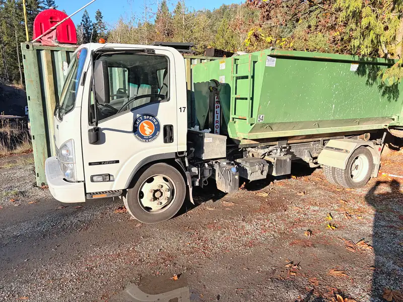 Salt Spring Garbage Isuzu bin truck #17 carrying a green roll-off bin